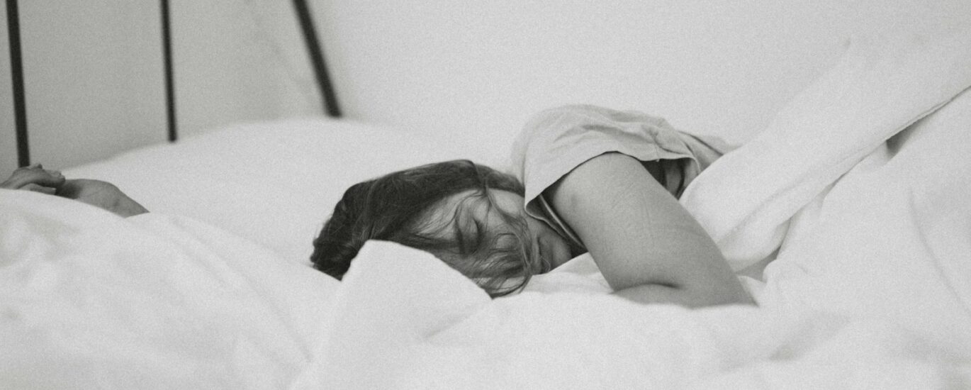 grayscale photo of sleeping woman lying on bed