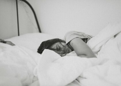 grayscale photo of sleeping woman lying on bed